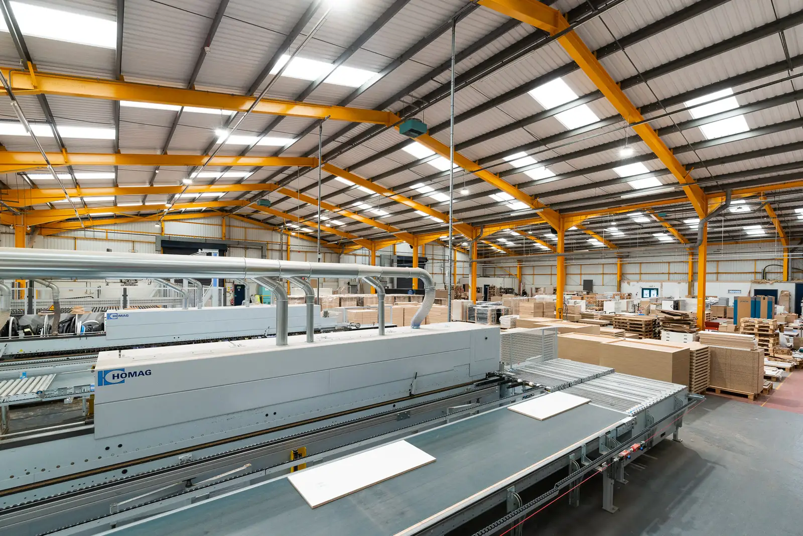 Panel processing line and edgebander inside the Watson joinery factory with orange steel frame
