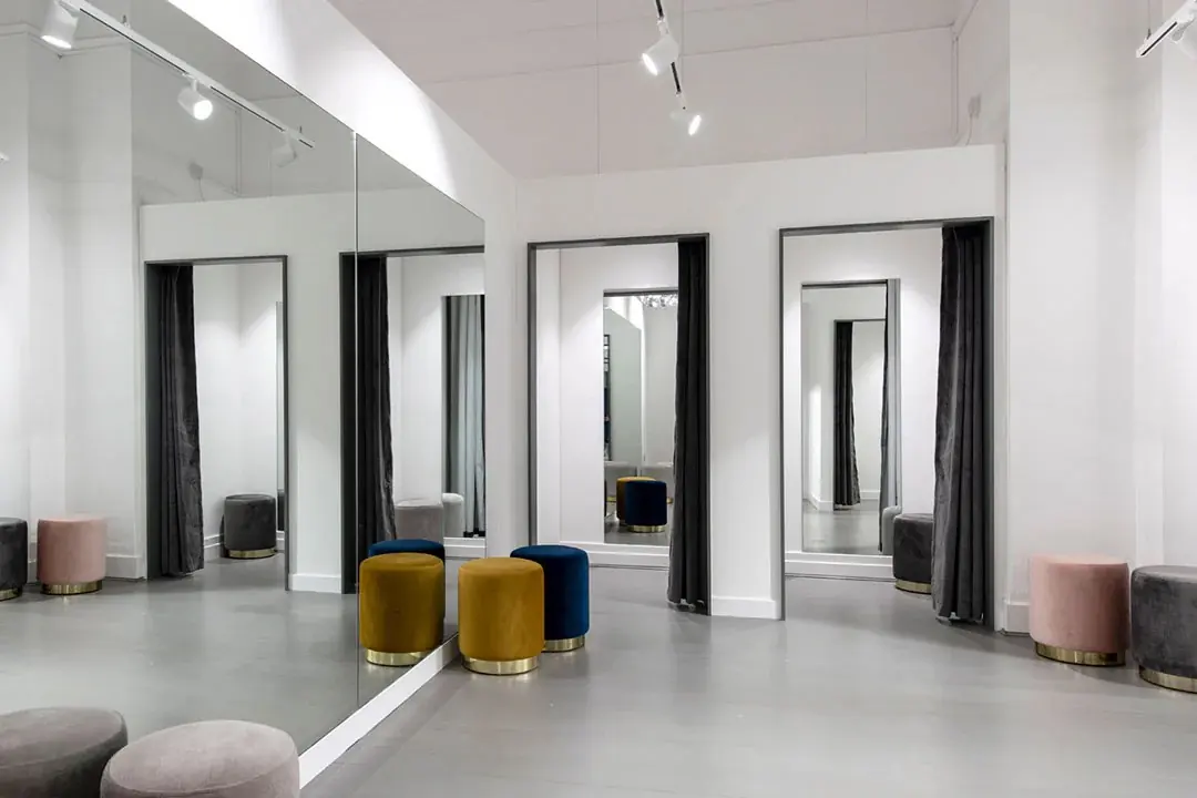 Boutique fitting rooms with curtained cubicles, mirrored walls and velvet pouffes