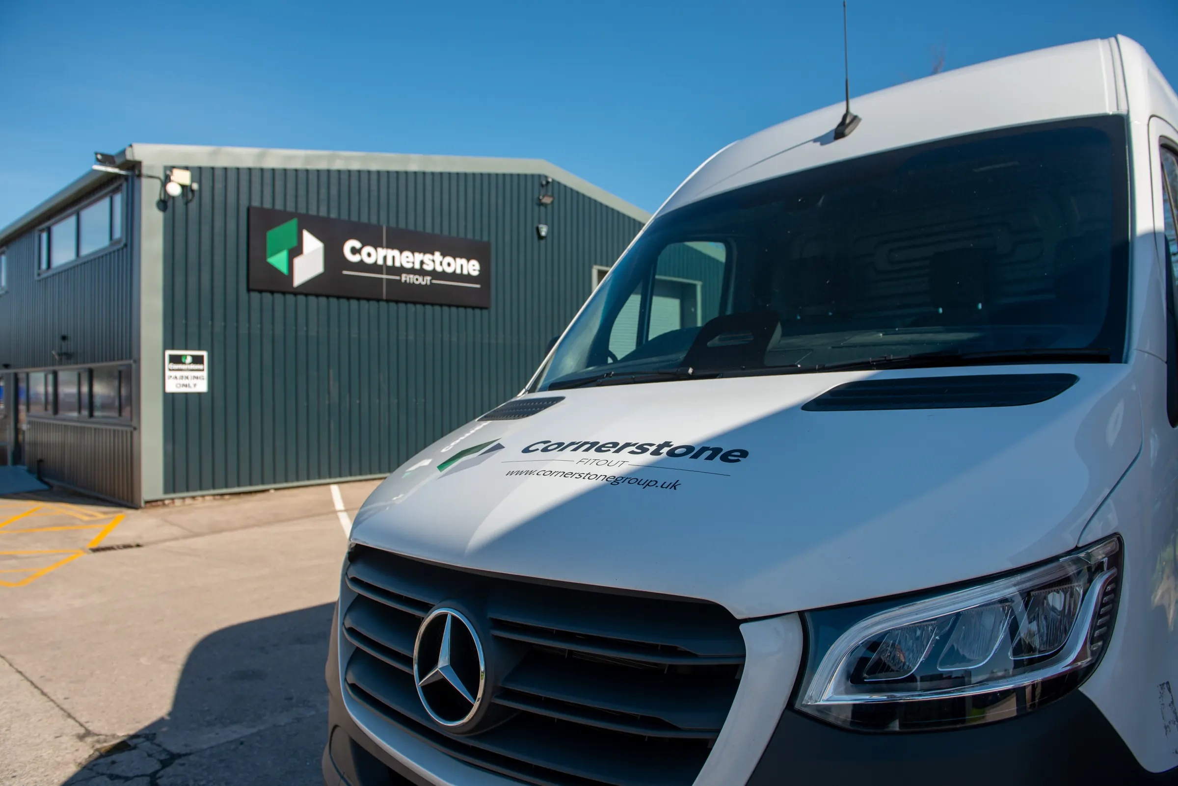 Cornerstone liveried Sprinter van outside the green clad Cornerstone building