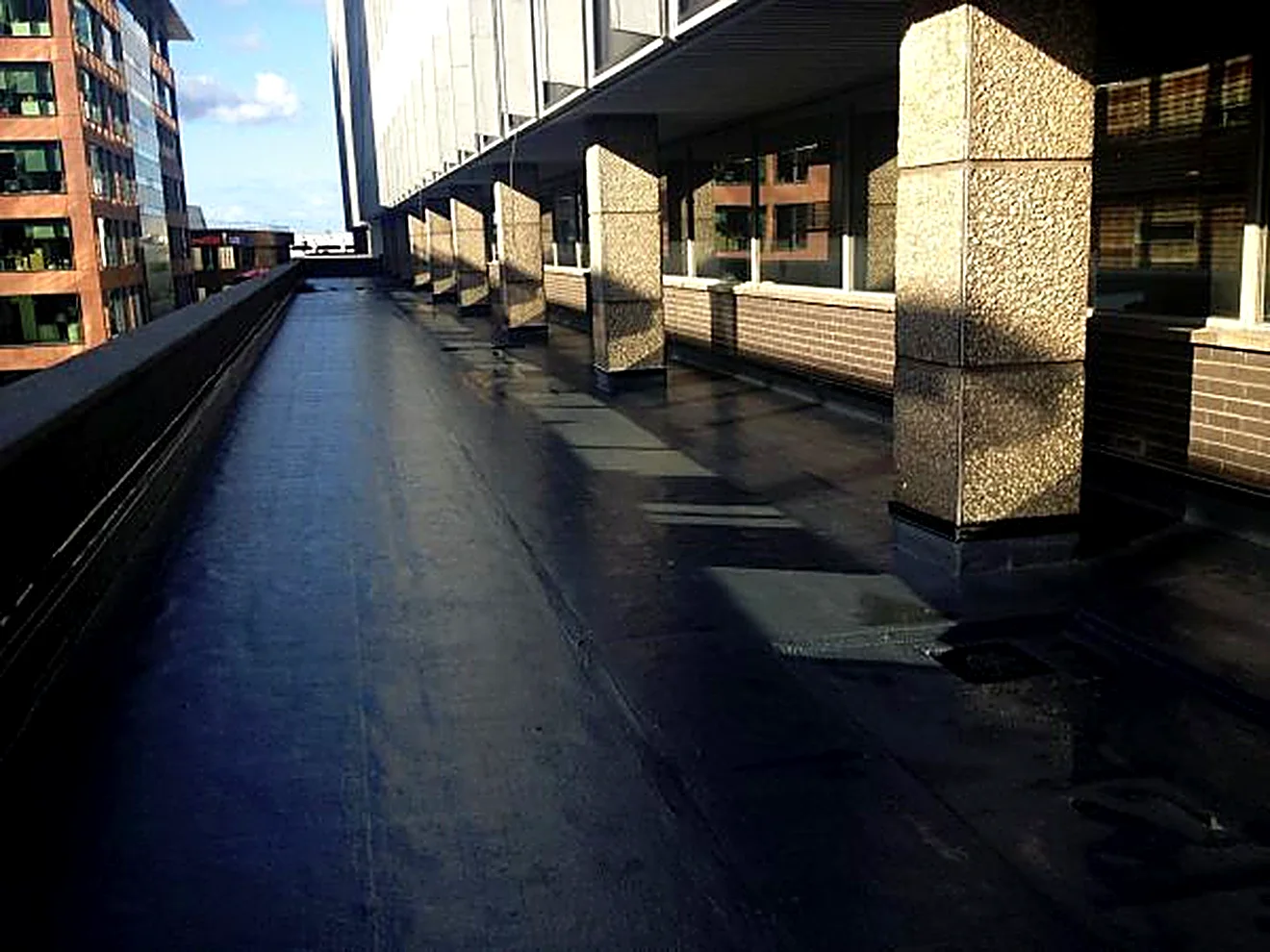 Seamless liquid roof alongside the stone columns of a city office building