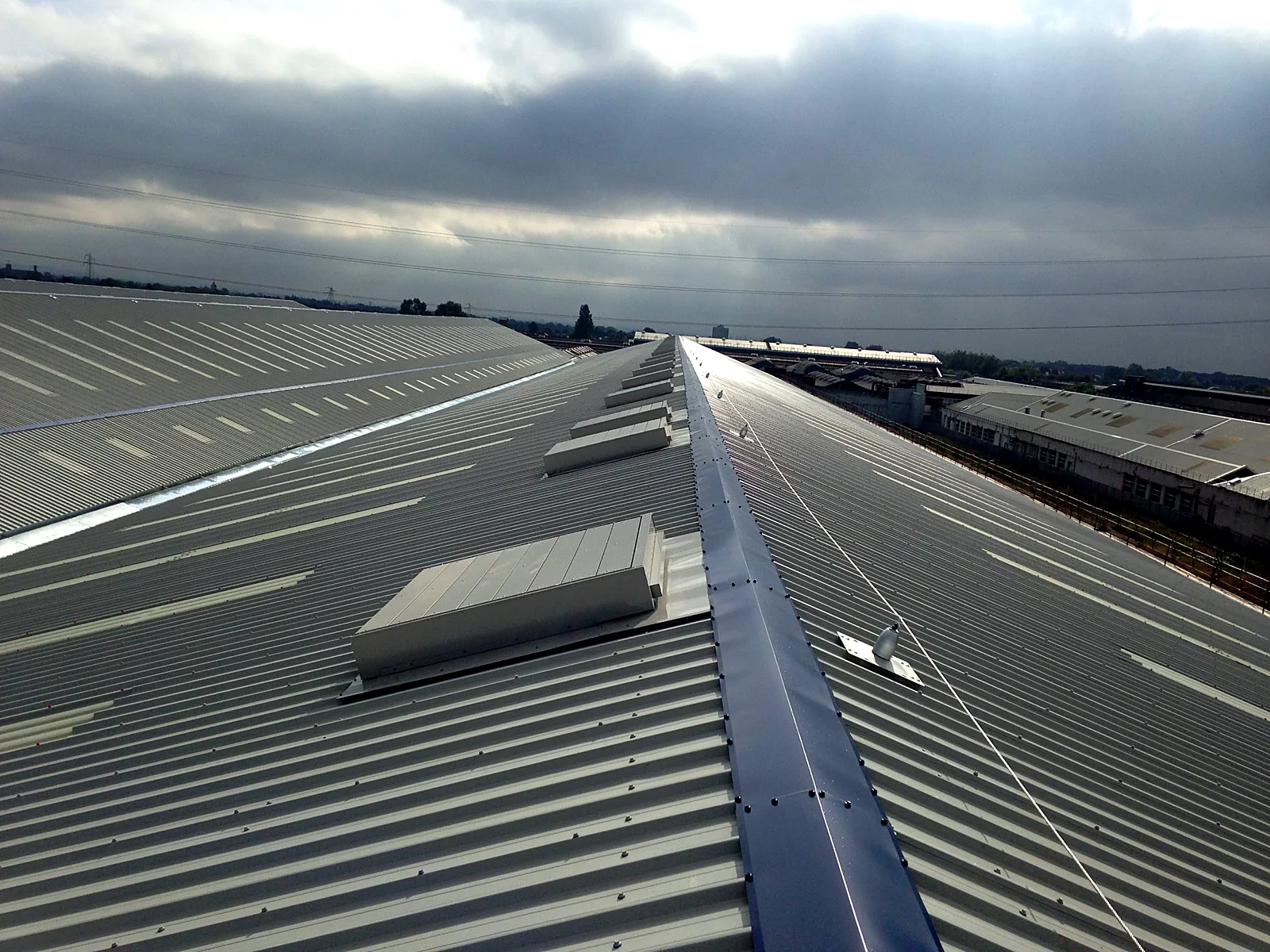 New grey metal roof with ridge capping and rooflights on the Mono Pumps building in Manchester