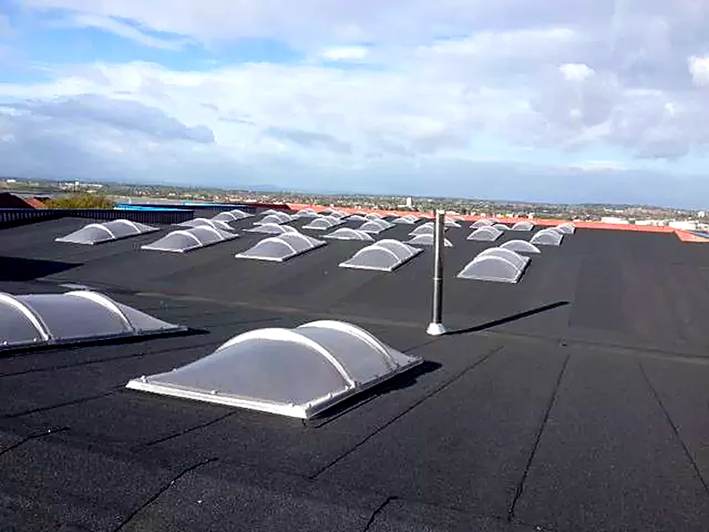 New felt roof with domed rooflights across a row of industrial units