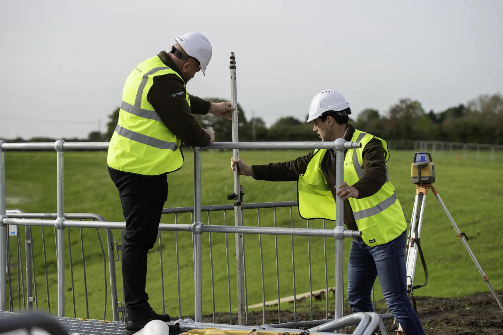 Cornerstone engineers in hard hats and hi-vis setting out with a levelling staff and laser