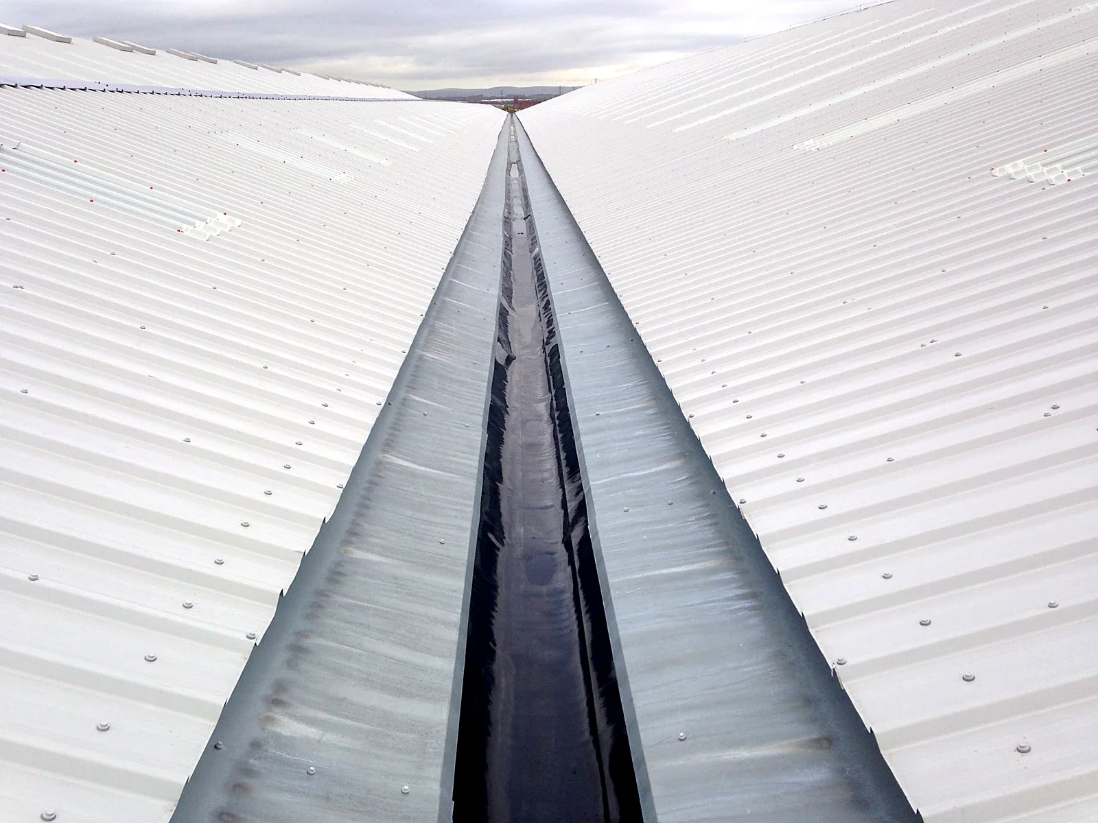 Lined valley gutter between two metal roof slopes