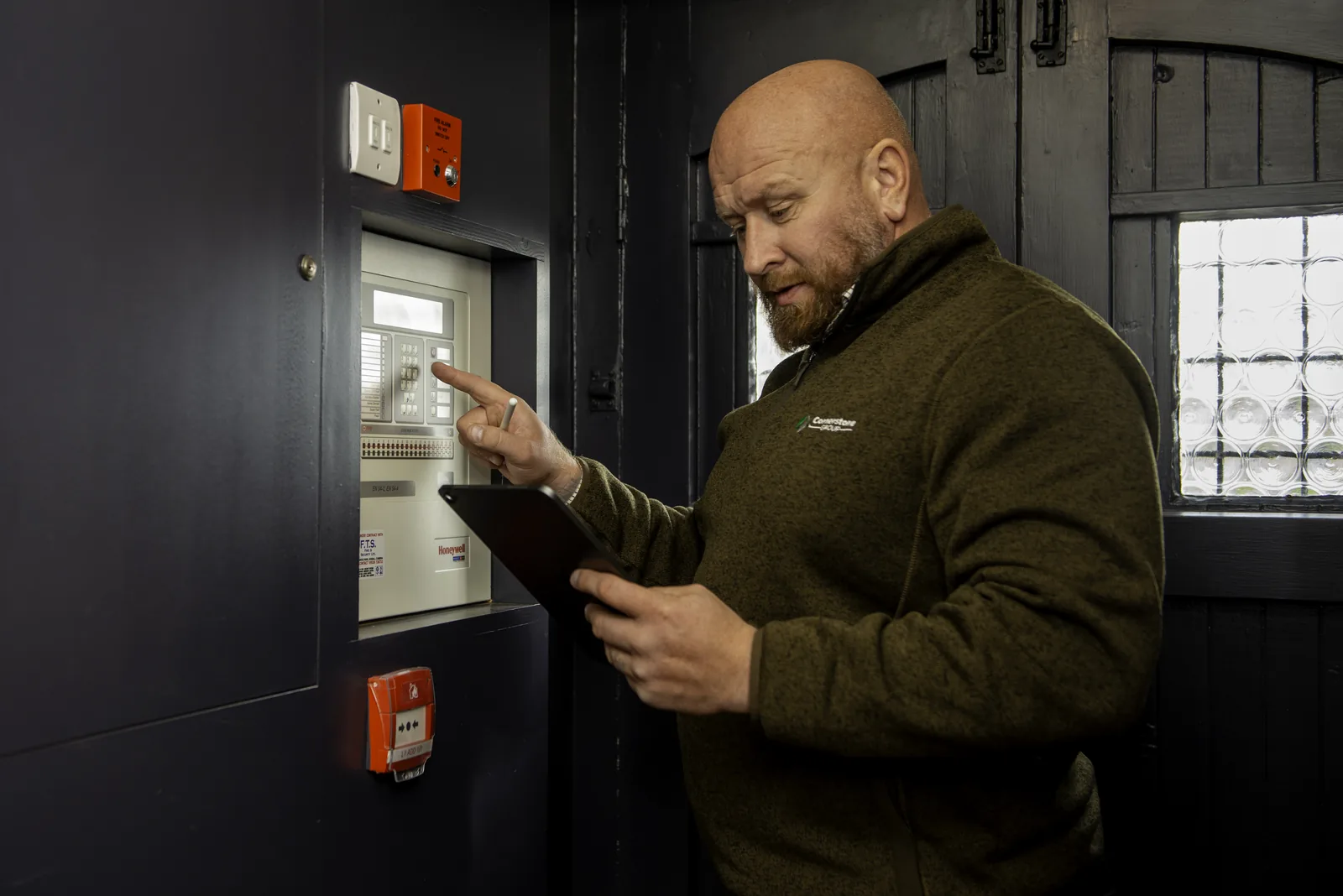 Cornerstone team member checking the fire alarm panel at Ye Horns Inn