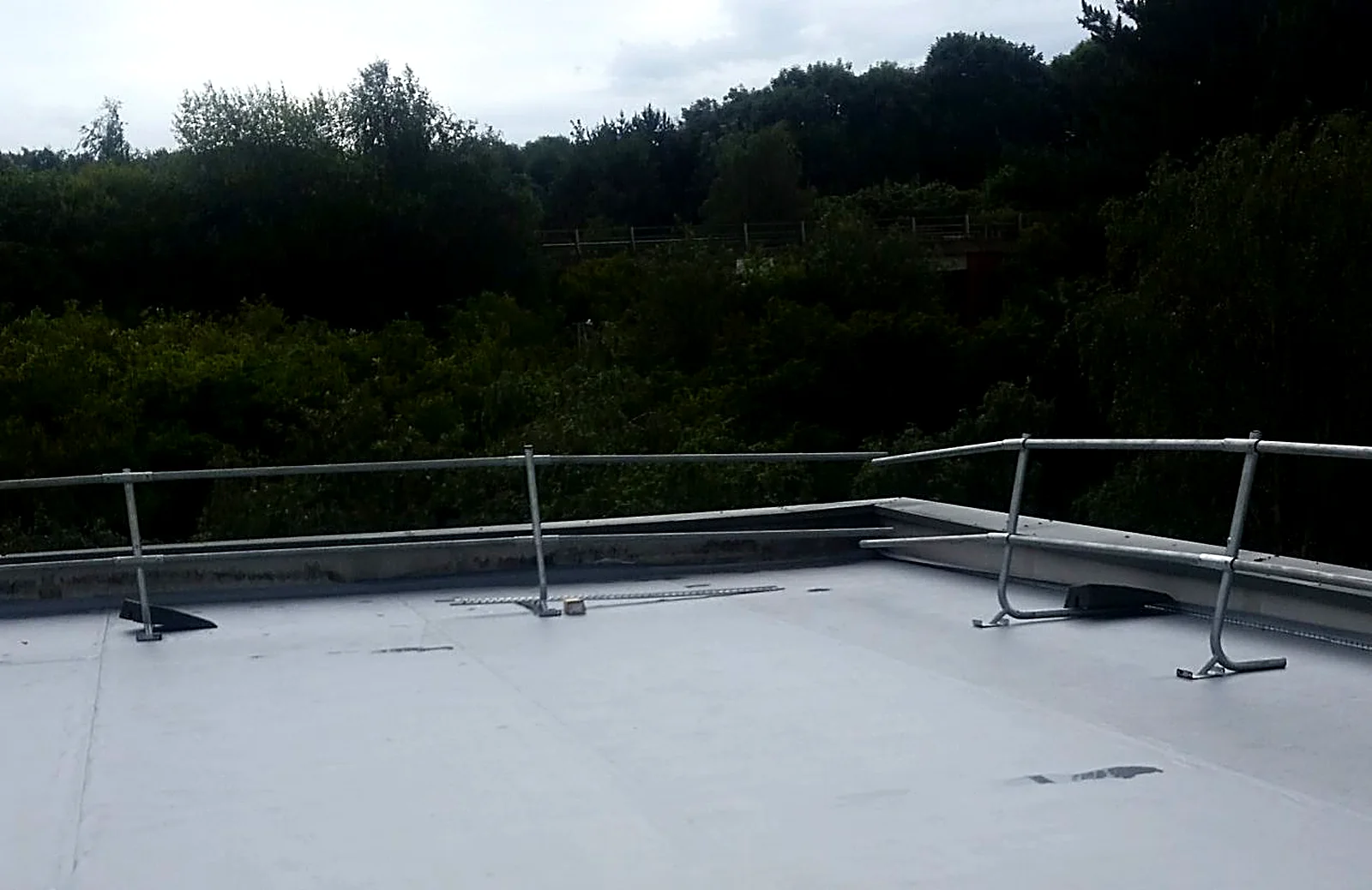 Single-ply flat roof with a perimeter safety guardrail