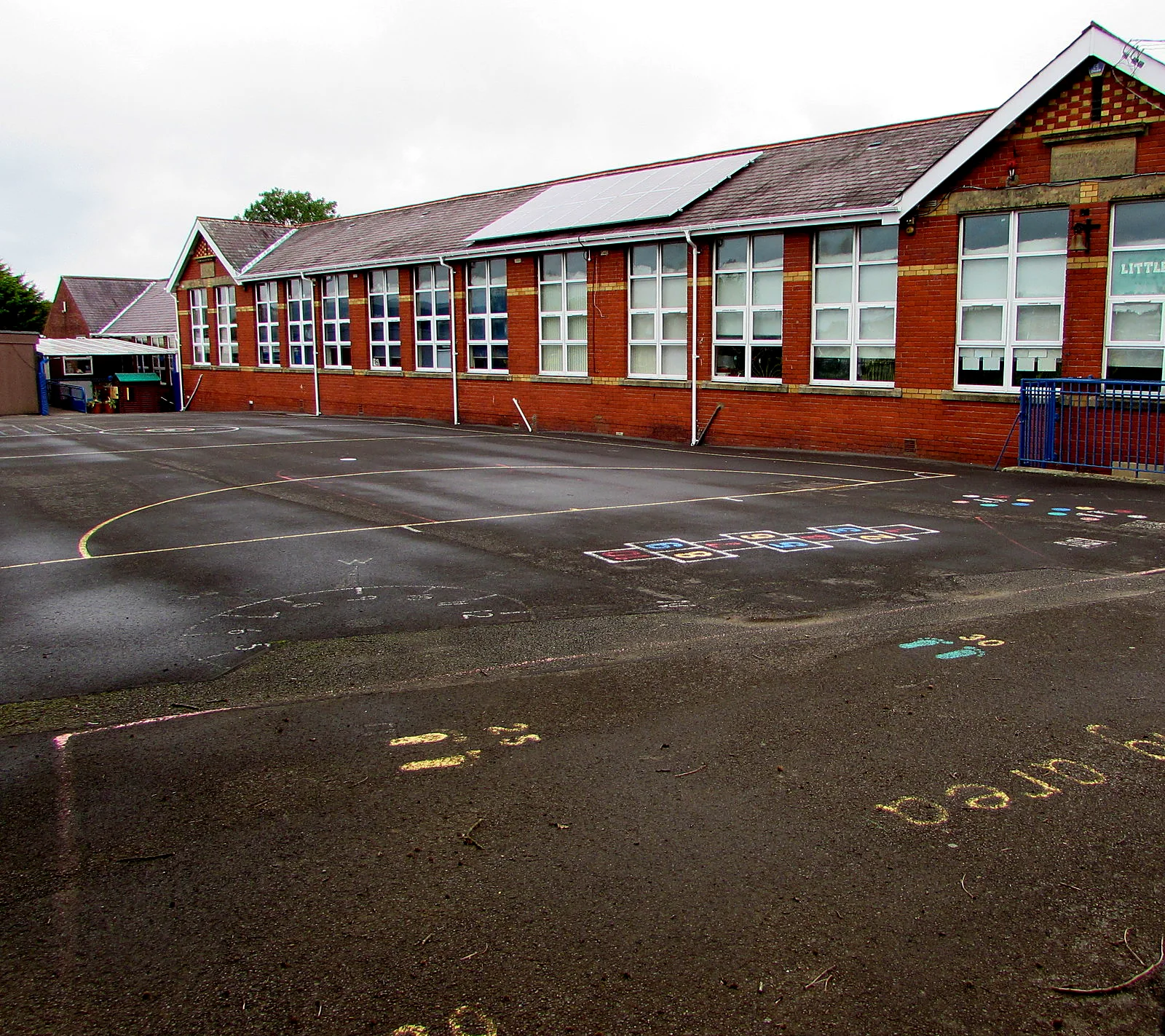 Red-brick primary school with solar panels on its roof above the playground