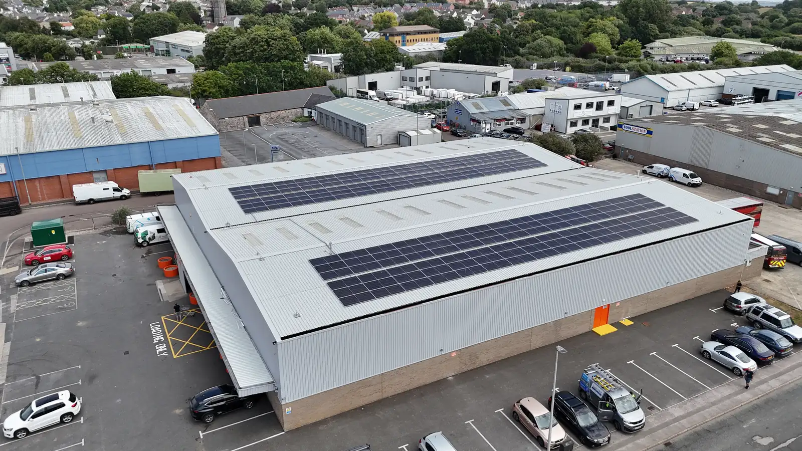 Aerial view of solar PV panels on an industrial unit roof surrounded by a busy car park