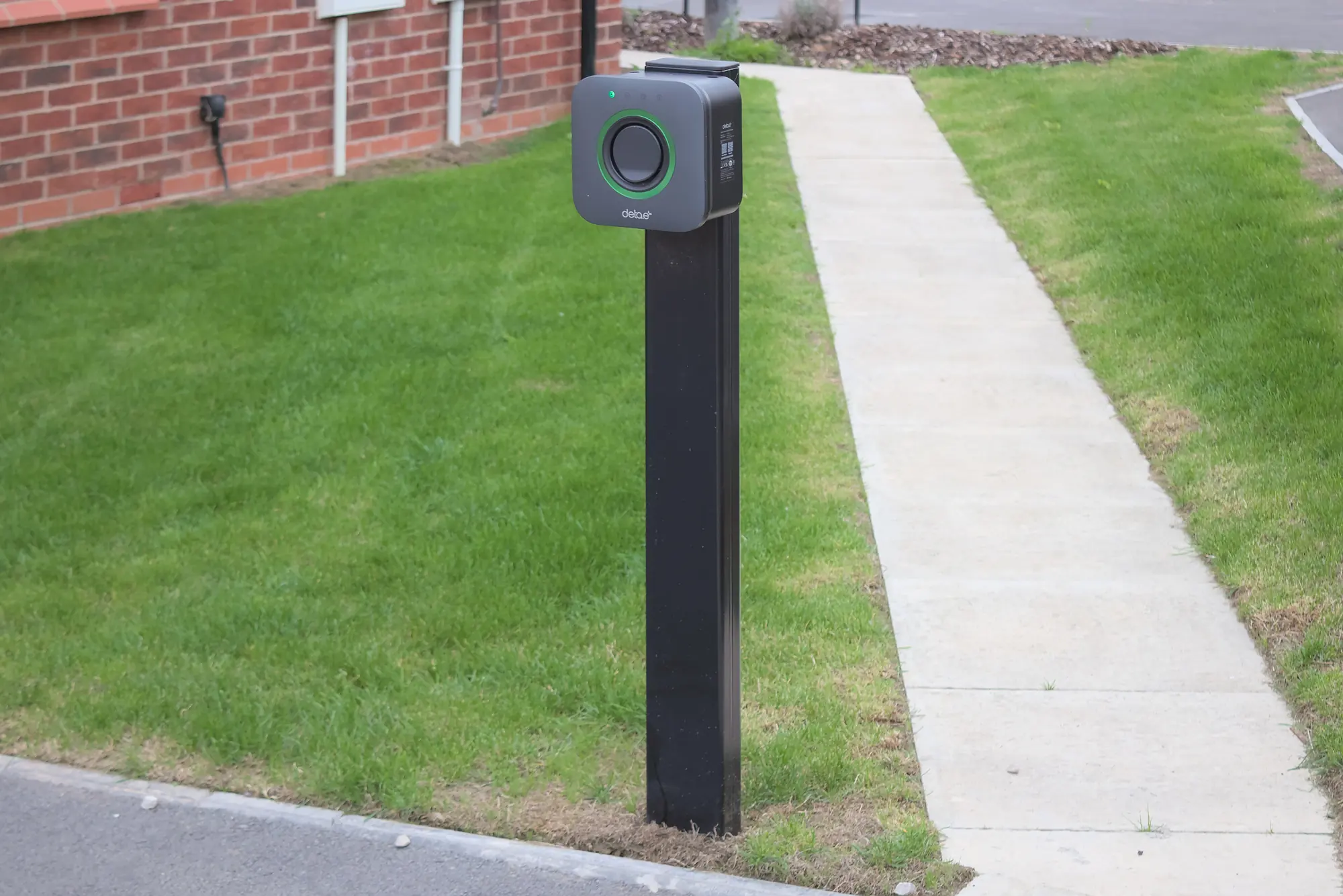 Pedestal-mounted EV charger beside a car park path