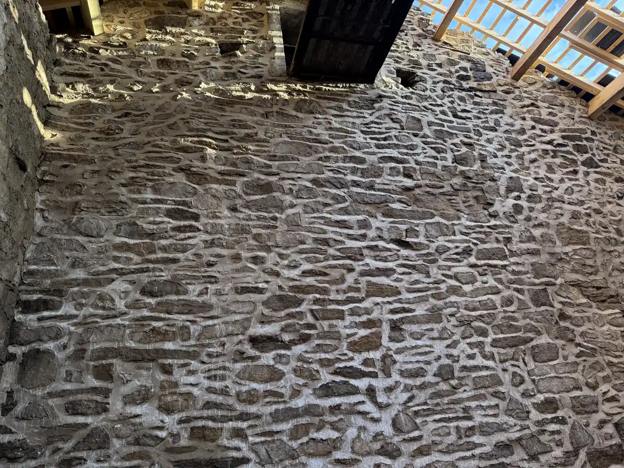 Interior stone wall of the barn after lime repointing, under new rooflights